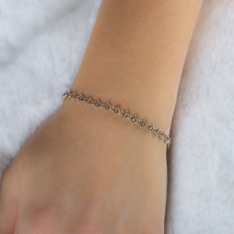 This 18k yellow gold bracelet features tanzanite beads woven throughout a delicate chain. The bracelet features a lobster clasp closure.