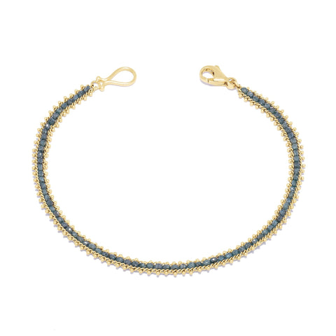This delicate 18k yellow gold bracelet is delicately woven with blue diamond beads throughout. The bracelet is finished with an 18k yellow gold lobster clasp.