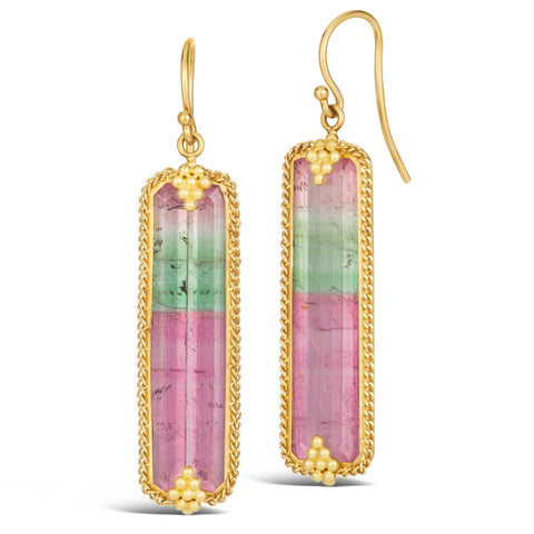 A pair of long rectangular tourmaline earrings, featuring pale pink and green hues. The stones are set in 18k yellow gold chain wrapped bezels with two beaded prongs. The earrings hang on French hook closures.