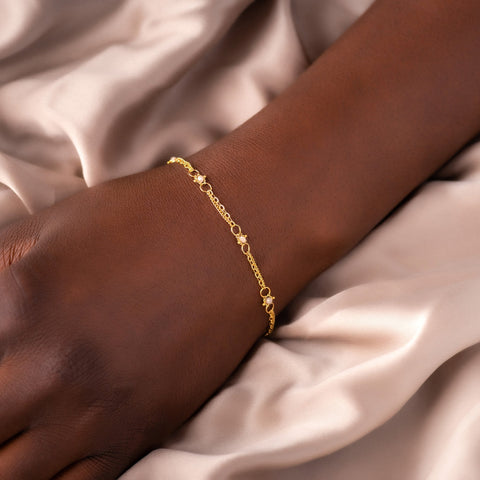 This delicate 18k yellow gold chain bracelet is dotted with silver diamond beads throughout. The bracelet is finished with a lobster clasp closure.