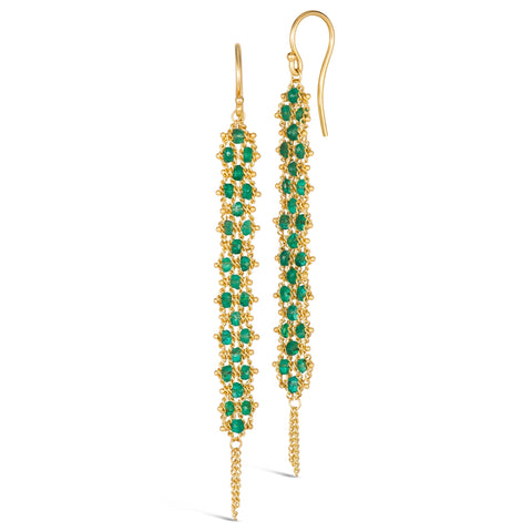 A pair of long green emerald earrings features a woven lattice pattern and two dangling chains at the bottom of the earring. The earrings fasten with french hook closures.