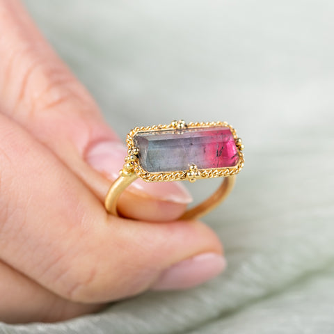 Gold ring with a watermelon tourmaline gemstone on a blurred background