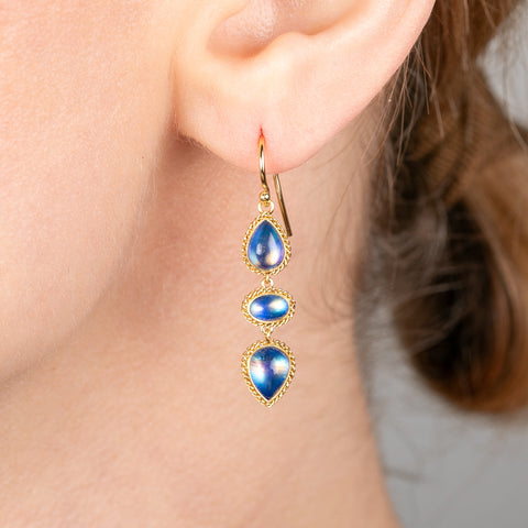 Gold earrings with moonstone stones worn by a person
