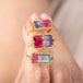Three tourmaline gemstone rings with gold settings on a hand against a neutral background