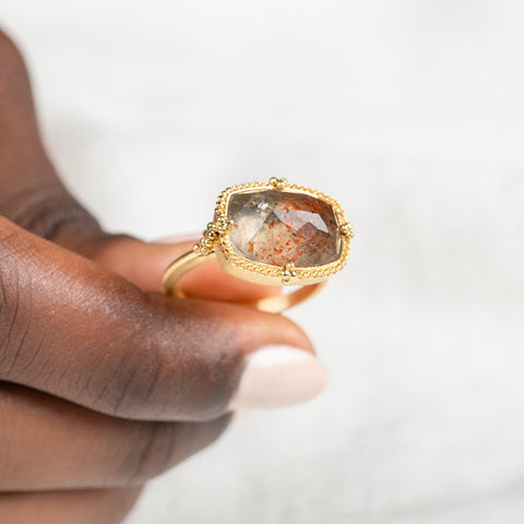 Gold ring featuring sunstone gemstone held in hand
