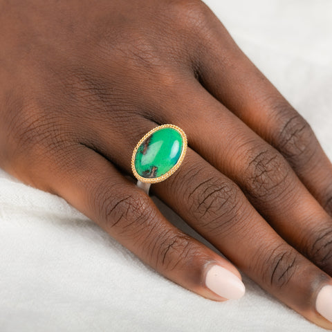 A gold and silver ring featuring an oval gem silica stone on a person's finger