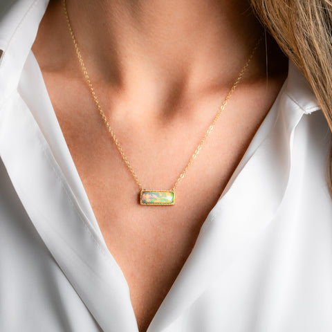 A gold necklace featuring an ethiopian opan worn on a person's necklace