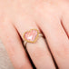Heart-shaped ring with rhodochrosite stone, gold setting and silver band on a person's finger