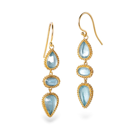 Gold earrings with blue aquamarine gemstones on a white background