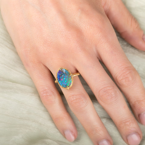 Gold ring with a colorful boulder opal stone on a hand