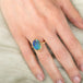 Gold ring with a colorful boulder opal stone on a hand