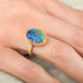 Gold ring with a colorful boulder opal stone on a hand
