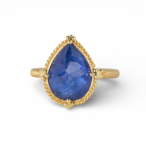 Gold ring with a teardrop-shaped tanzanite gemstone on a white background