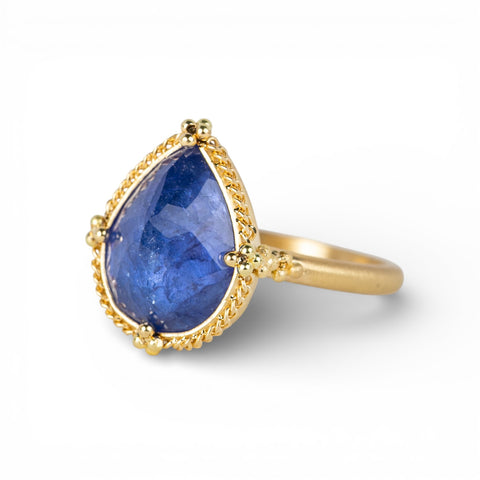 Gold ring with a teardrop-shaped tanzanite gemstone on a white background
