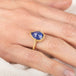 Gold ring with a teardrop-shaped tanzanite gemstone on a person's finger
