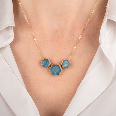 Necklace with hexagonal aquamarine stones and gold accents on a person's neck