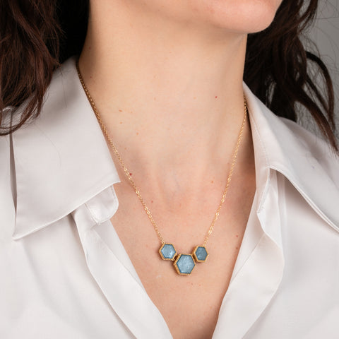 Necklace with hexagonal aquamarine stones and gold accents on a person's neck