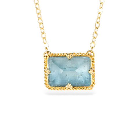 Gold necklace with an aquamarine gemstone and gold chain on a white background