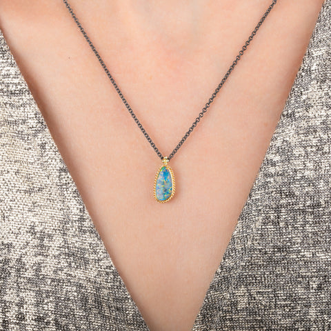 Australian opal doublet necklace with 18k gold bezel and oxidized silver chain, worn on a person's neck.