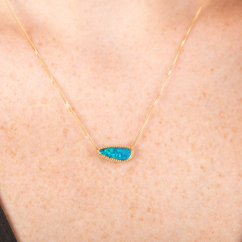 Handmade 18k gold necklace with an opal doublet pendant on a person