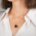 Gold necklace featuring a jasper gemstone carved into a black bear face worn on a model's neck.