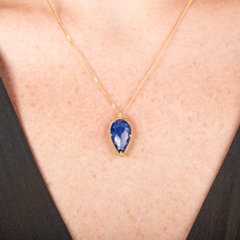 Handmade gold necklace with a blue tanzanite teardrop pendant on a person