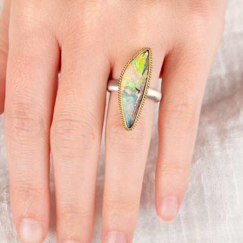 Hand wearing a boulder opal ring with 18k gold bezel and sterling silver band