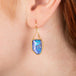 Gold earring featuring a boulder opal shown worn in an ear