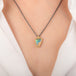 A necklace featuring a boulder opal set in an 18k gold bezel and suspended from an oxidized silver chain, worn on a person's neck.