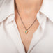 A necklace featuring a boulder opal set in an 18k gold bezel and suspended from an oxidized silver chain, worn on a person's neck.