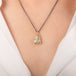 A necklace featuring a boulder opal set in an 18k gold bezel and suspended from an oxidized silver chain, worn on a person's neck.
