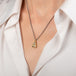 A necklace featuring a boulder opal set in an 18k gold bezel and suspended from an oxidized silver chain, worn on a person's neck.