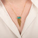 Gold necklace with a boulder opal gemstone pendant draped with a gold tassel on a person