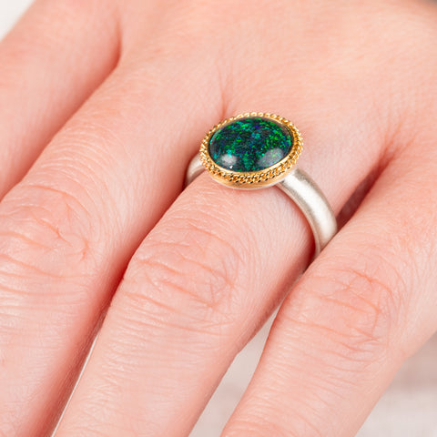 Close up of a hand wearing an andamooka opal ring with gold bezel and sterling silver band