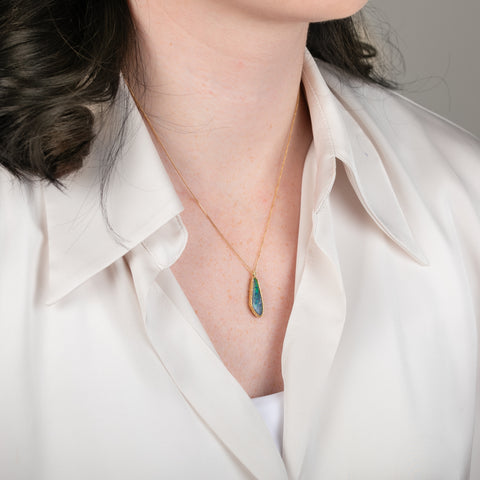 Boulder opal pendant necklace in a gold bezel on a person