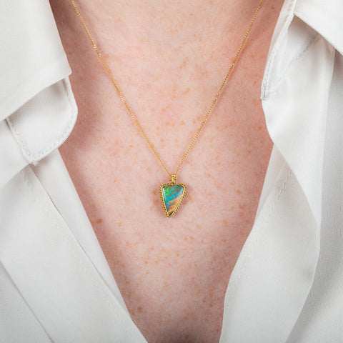Gold necklace with a boulder opal gemstone on a person