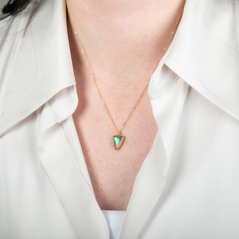 Gold necklace with a boulder opal gemstone on a person