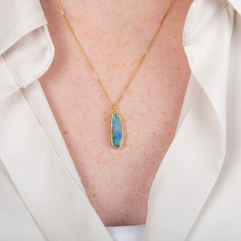 Handcrafted boulder opal and 18k gold necklace on a person