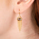 Gold earrings featuring brown diamonds and gold chain tassels, shown worn in a person's ear.