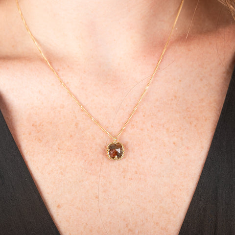 Necklace with a natural brown diamond set in a handmade gold bezel on a person