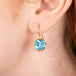 Gold earring featuring a moonstone carved as a moon face, worn in a person's ear.