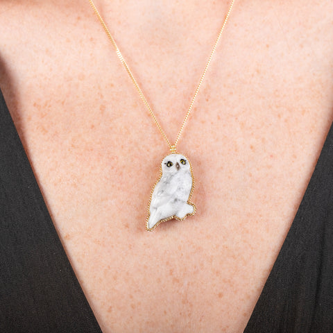 Handmade gold necklace featuring a hand carved owl quartz pendant worn on a persons neck.