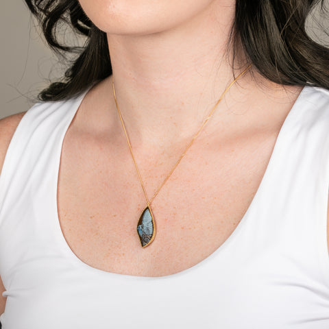 Carved phoenix boulder opal necklace in a gold setting worn on a person