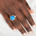 Gold and silver ring with blue ceruleite stone on a person's hand on a white background
