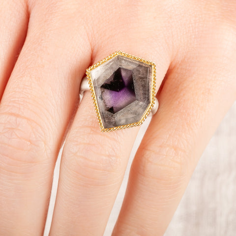 Close up of person wearing a handmade fine jewelry amethyst gemstone ring set in 18k gold with a sterling silver band