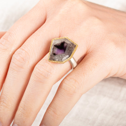 Close up of person wearing a handmade fine jewelry amethyst gemstone ring set in 18k gold with a sterling silver band
