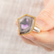 Close up of person holding a handmade fine jewelry amethyst gemstone ring set in 18k gold with a sterling silver band