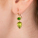 Gold earring featuring chrome diopside and peridot gemstones, shown worn in a person's ear.