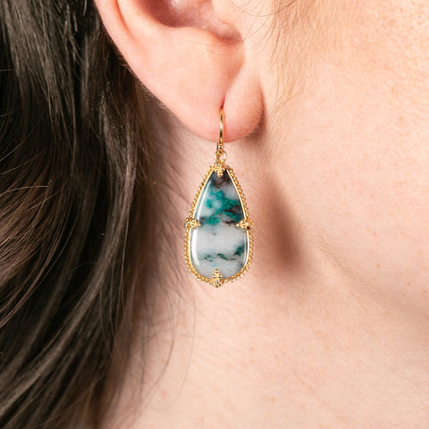 Teardrop-shaped earring with a chrysocolla stone worn by a person.