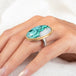 A gold and silver ring featuring a chrysocolla in quartz gemstone, worn on a person's finger.